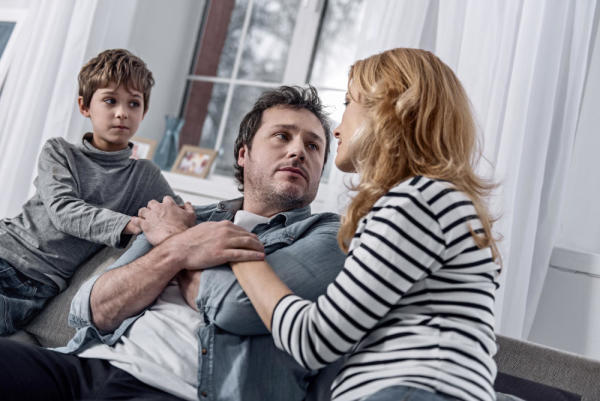 A man's young son and wife gather around him on the couch to address his substance use problem