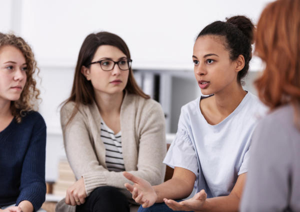 Women living in recovery housing gather for a group therapy session on addiction recovery